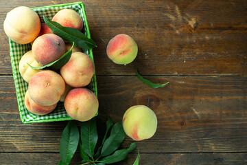 Naklejka na ściany i meble Ripe peaches in basket on wooden background. Home harvest from your own garden.