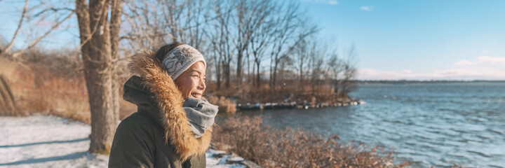 Winter cold Asian woman happy smiling in cold weather on outdoor walk sunlight in forest nature...