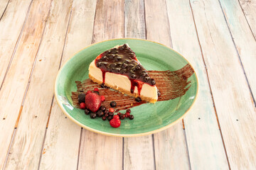Amazing presentation of cheesecake with red berry jam and berries with strawberries on the green plate