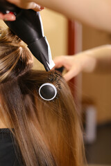 Fototapeta premium Stylist doing hairstyle beautiful brunette