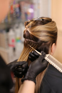 Professional female hairdresser applying color to female customer at design hair salon, woman having her hair dyed, Hair dye colouring in process