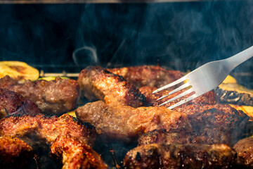 Grilling meat rolls called mici or mititei with vegetables on char barbecue. Charcoal grill with...