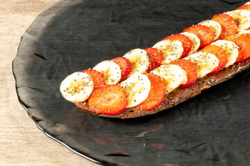 Delicious toast spread with chocolate and accompanied by slices of banana and strawberry along with various grains Healthy breakfast concept.