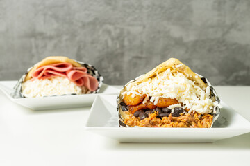 Two Venezuelan arepas filled with Pablellon criollo: Sausage meat, beans, plantains and cheese. Ham and cheese. Typical Venezuelan food.
