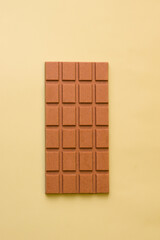 Bar of milk veggie chocolate on a green background. View from above. Minimalism