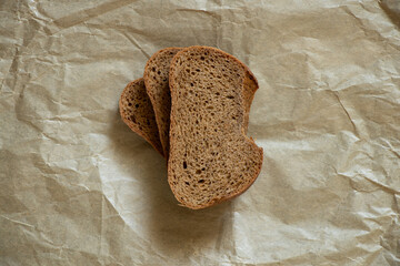 a piece of black bread lies on brown paper