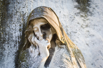 Primo piano della statua di una donna triste su una tomba del cimitero delle Porte Sante di Firenze
