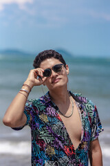 young woman poses for the camera with sunglasses on a summer day at the beach