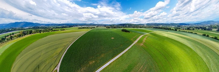 Abstract panoramic aerial view in a forest and field with fantastic beautiful clouds and curvature of space like a small planet