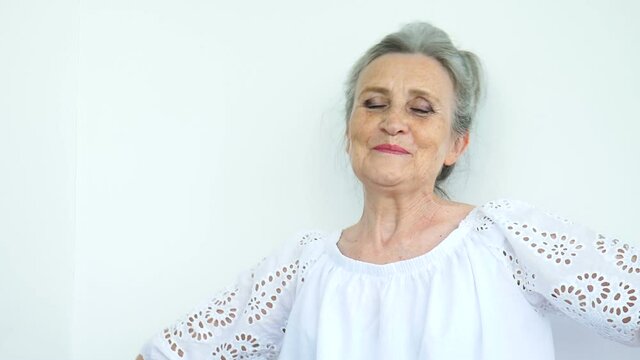 Beautiful old grandmother with grey hair and face with wrinkles is looking at the camera with smile on white background, mothers day, happy retirement