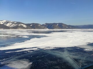 Obraz premium transparent ice of a lake in winter among snow-capped mountains
