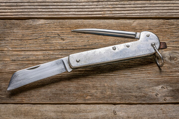 vintage sailor knife with marlinespike and straight blade (made in Poland in 1970s) against rustic wood, signs of heavy use and abuse