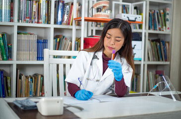 Shot of a southeast Asian girl working in a laboratory with the test tube with fluid in her hands.