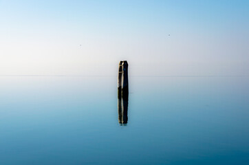 Una briccola e il suo riflesso in una giornata di bonaccia a Pellestrina, nella laguna di Venezia