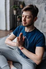 A young man sitting in meditation with his hands folded in a yoga mudra