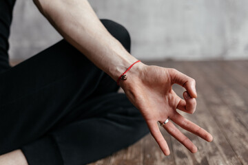 A young man sitting in meditation with his hands folded in a yoga mudra