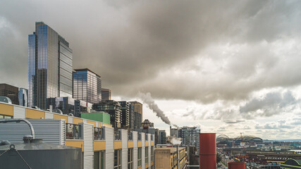 Cityscape of Seattle with dark clouds and dark vapor rising from smoke stack