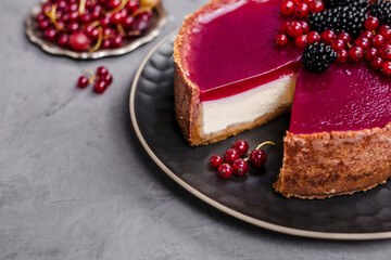 cheesecake topped with raspberry jelly, garnished with blackberries and red currants 