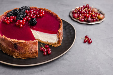 cheesecake topped with raspberry jelly, garnished with blackberries and red currants 