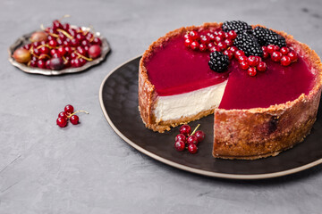 cheesecake topped with raspberry jelly, garnished with blackberries and red currants 