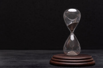 Hourglass on black background. Urgency and outcome of time. Time management.
