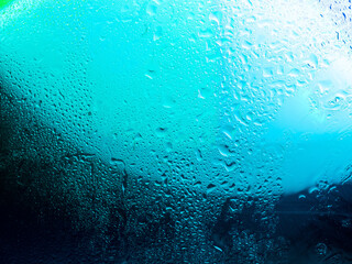Misted glass, colorful abstract rainbow colored mist rain drops dew drops water droplets condensation on rainbow tinted glass window