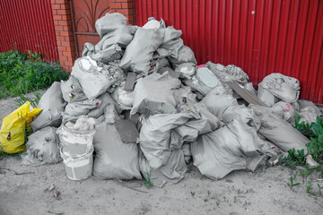 A large pile of construction debris near the fence of a residential building.