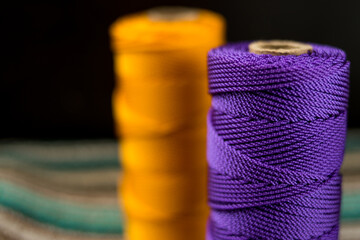 Close up of some different colorful rolls of thread on a colorful striped  mat