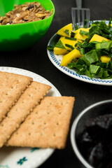 Healthy mango and spinach salad, soda cookies and some prunes on a black wooden table 