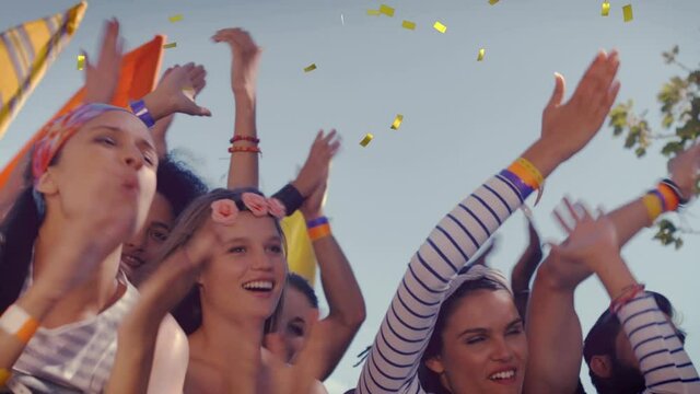 Animation of gold confetti falling over people having fun at summer music festival