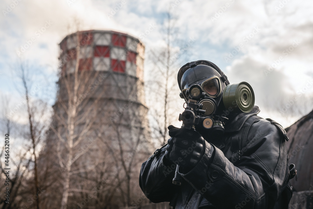 Wall mural Post apocalypse soldier with a rifle and in the gas mask on the factory chimney background.