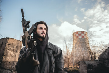 Post apocalypse soldier with a rifle and in the gas mask on the factory chimney background.