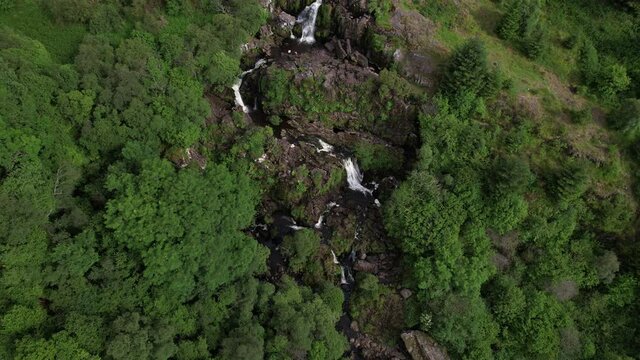 Aerial footage of the Loup of Fintry waterfall, near the village of Fintry in Central Scotland. People wild-water swimming in the pools at the bottom of the cascade.