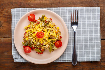Risotto with mushrooms in a plate on a wooden background on a checkered napkin and fork.