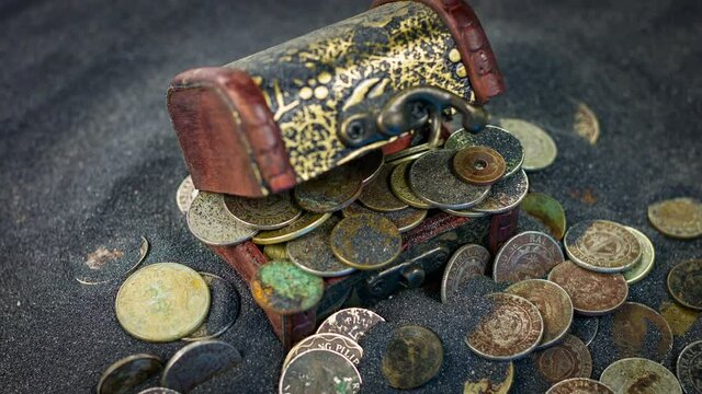 Old casket and old coins on a sand background close up rotation.