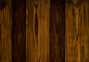 Obraz premium Background of an old natural wooden darken embossed fence of beech texture inside vintage, retro proper vertical warm rural interior with wood, shadows,