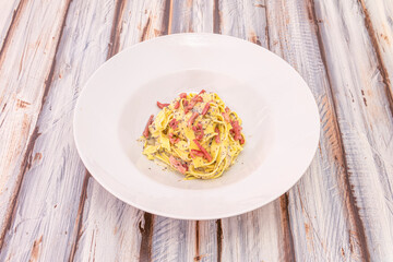 Italian tagliatelle carbonara recipe with truffle on white deep plate and vintage table