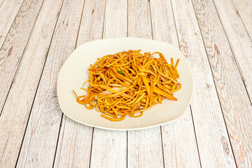Simple noodles sauteed with vegetables cooked in a Chinese restaurant with lots of soy sauce