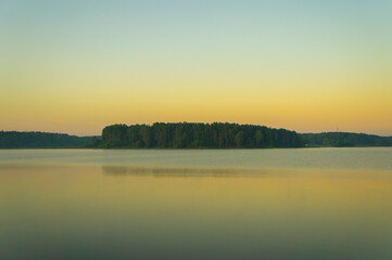 Calm beautiful sunrise over the lake with sky reflection in water