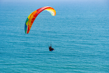 Paragliders with the beautiful blue open ocean, waves, and water behind them. Location near blacks beach, San Diego County, California.