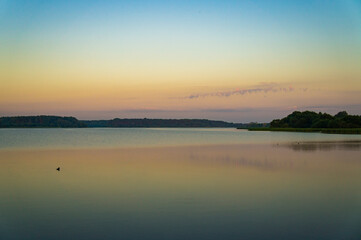 Calm beautiful sunrise over the lake with sky reflection in water