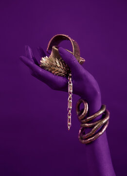 magenta woman's hand with gold jewelry. Oriental Bracelets on a black painted hand.