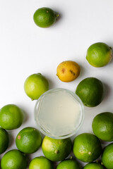 Limones y vaso con limonada en fondo blanco 