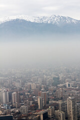 Mountain top covered in snow above the pollution clouds of urban area city in Santiago, Chile