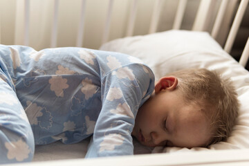 top view Cute little 2-3 years preschool baby boy kid sleeping sweetly in white crib during lunch...