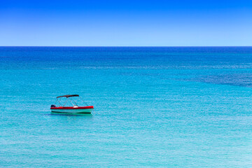 Fototapeta na wymiar Lone boat in the Mediterranean Sea in the resort village of Protaras on the island of Cyprus. Landscape in the style of minimalism.