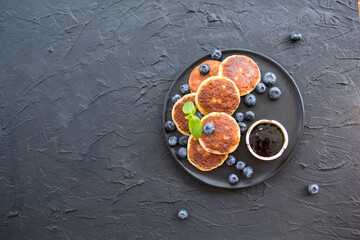 A healthy breakfast of cheese pancakes, berries, and honey. Creative atmospheric decoration