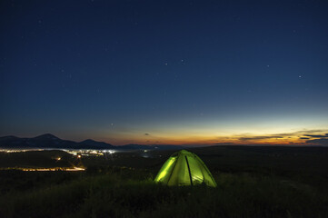 Fototapeta na wymiar Night landscape, tent against the background of the starry sky and city lights on a hill in Ukraine