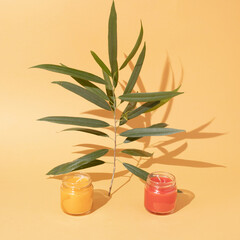Candle jars with green leaf on yellow background. Minimal arrangement.
