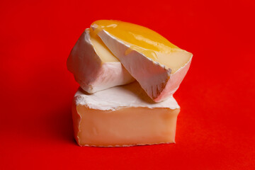 soft cheese with white mold and honey on a red background.